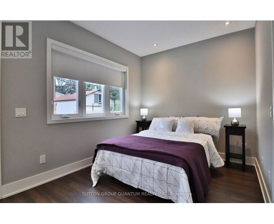 A bedroom with a large bed and a window overlooking a house.