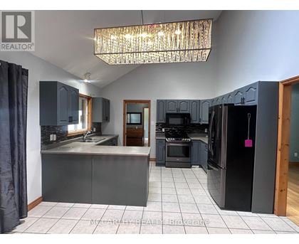 A kitchen with a black refrigerator and a chandelier hanging from the ceiling.
