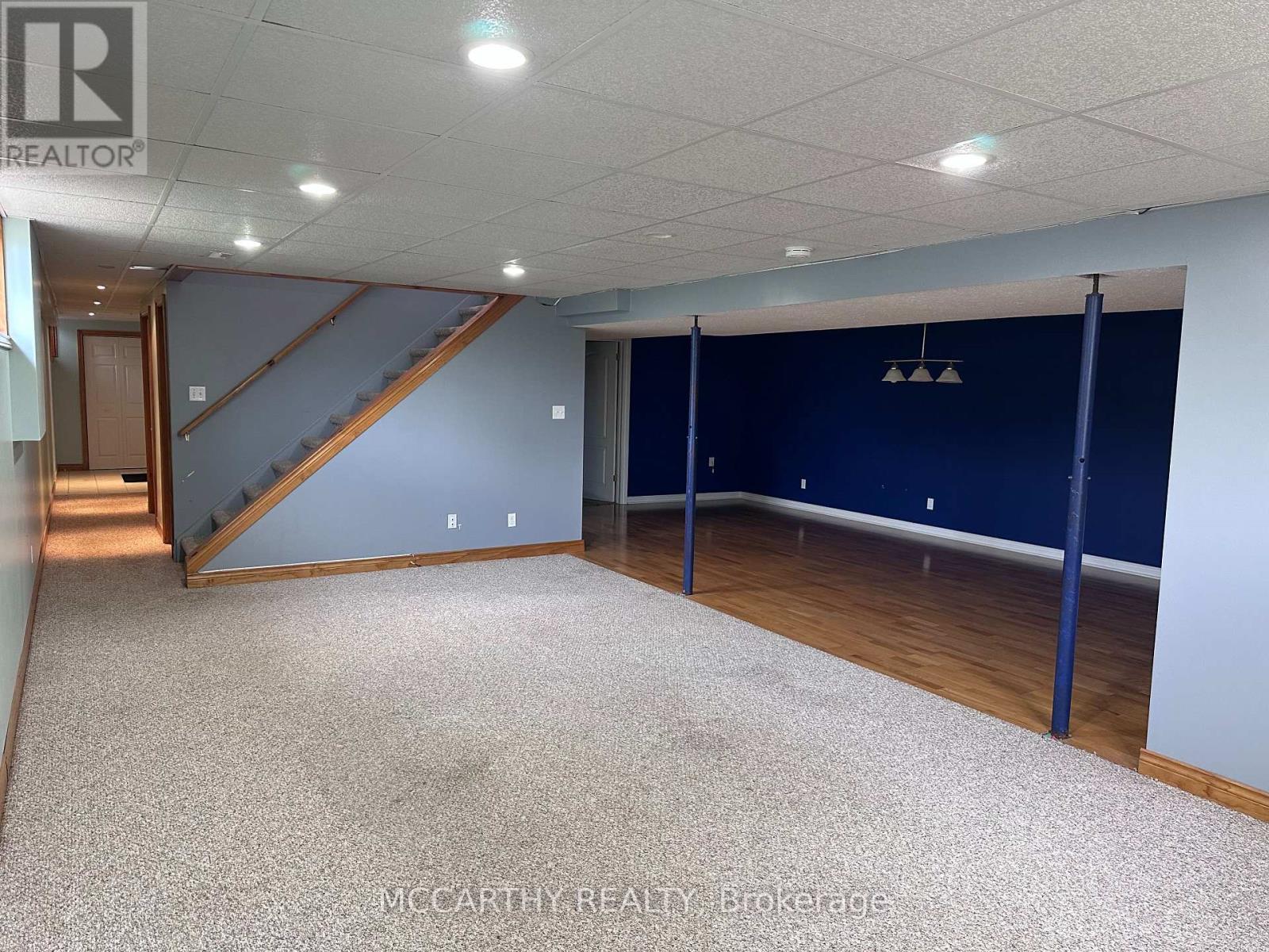 A spacious room with a staircase and a carpeted floor.