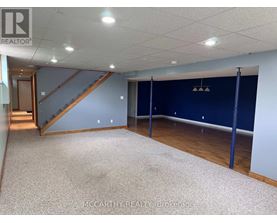A spacious room with a staircase and a carpeted floor.