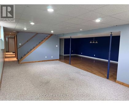 A spacious room with a staircase and a carpeted floor.