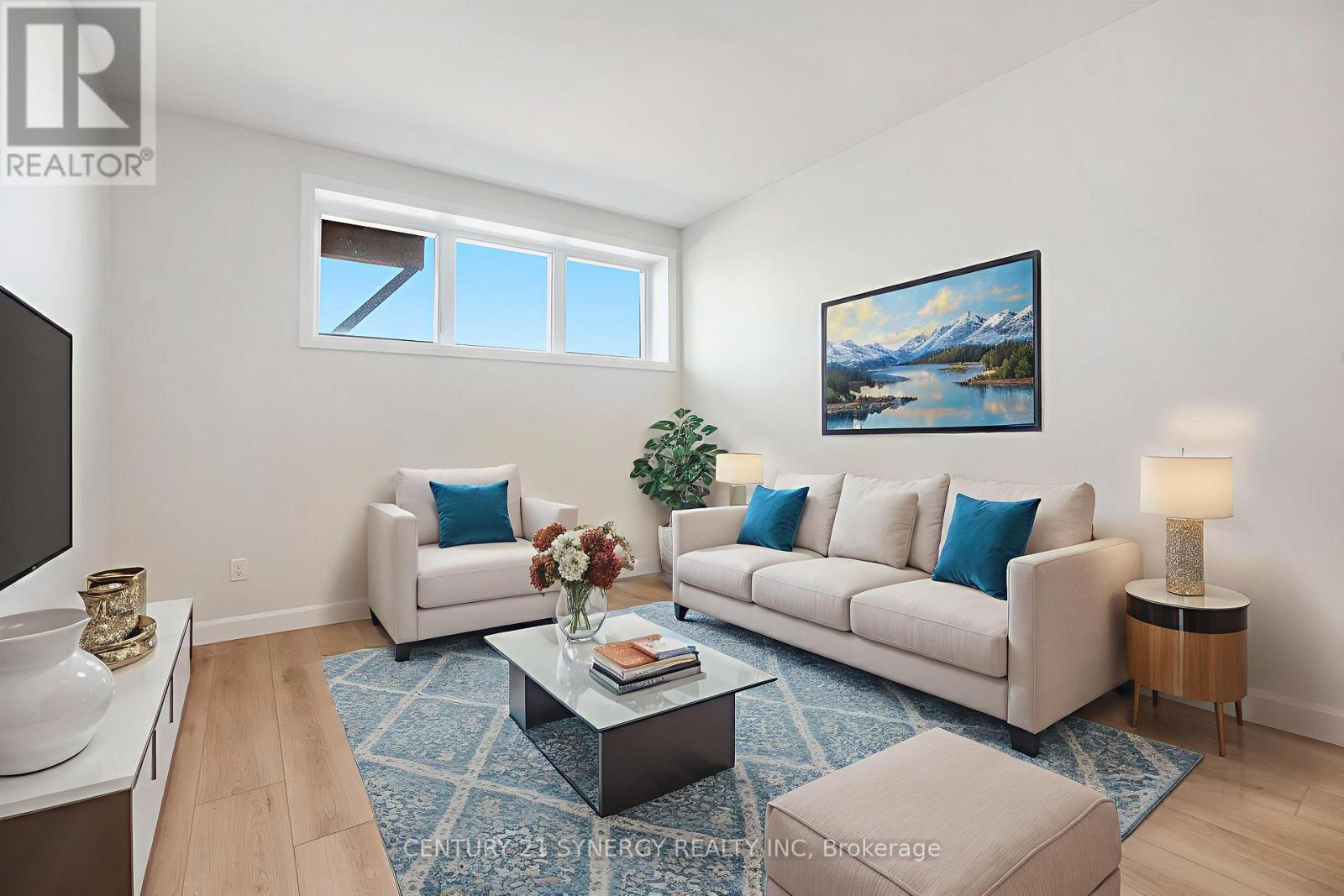 A living room with a white couch, a coffee table, and a painting on the wall.