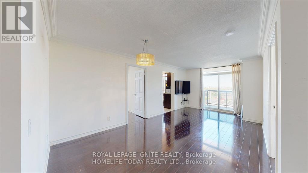 A spacious room with a wooden floor and white walls, furnished with a couch, a TV, and a bookshelf.