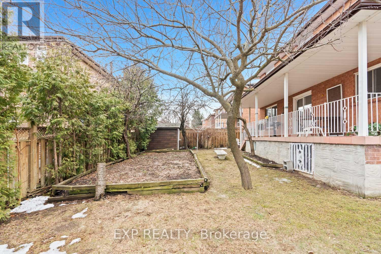 A backyard with a tree, a fence, and a building in the background.