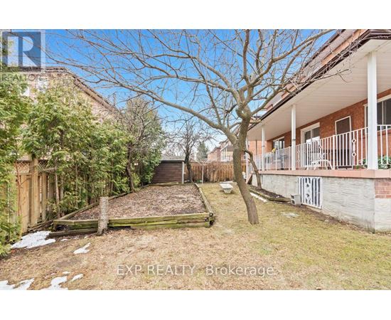 A backyard with a tree, a fence, and a building in the background.