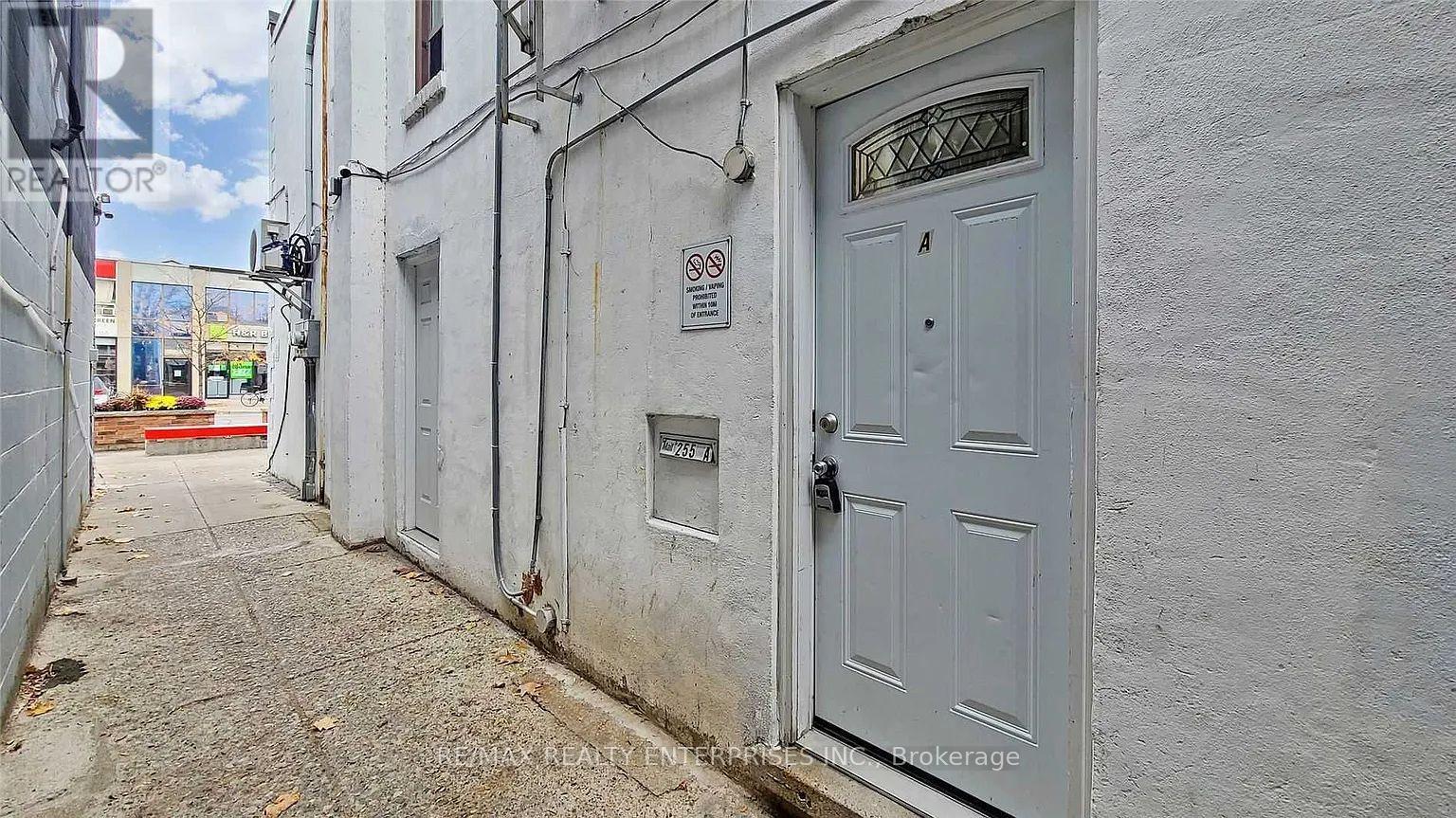 A narrow alley with a white door and a no parking sign.