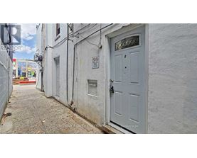 A narrow alley with a white door and a no parking sign.