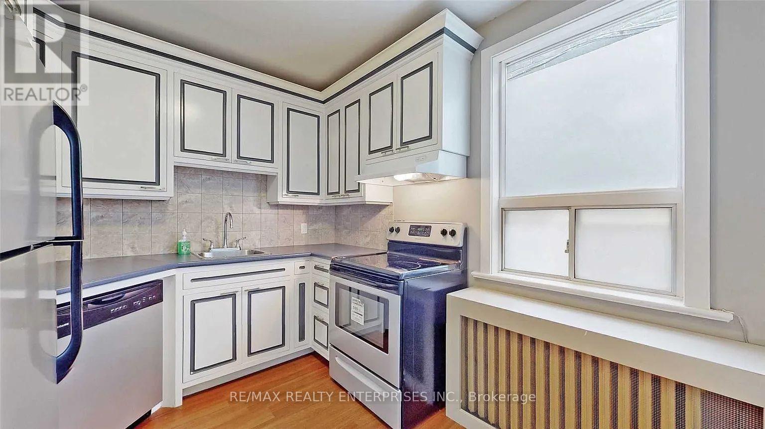 A kitchen with white cabinets and a black refrigerator.
