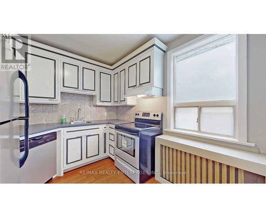 A kitchen with white cabinets and a black refrigerator.