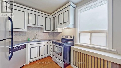 A kitchen with white cabinets and a black refrigerator.