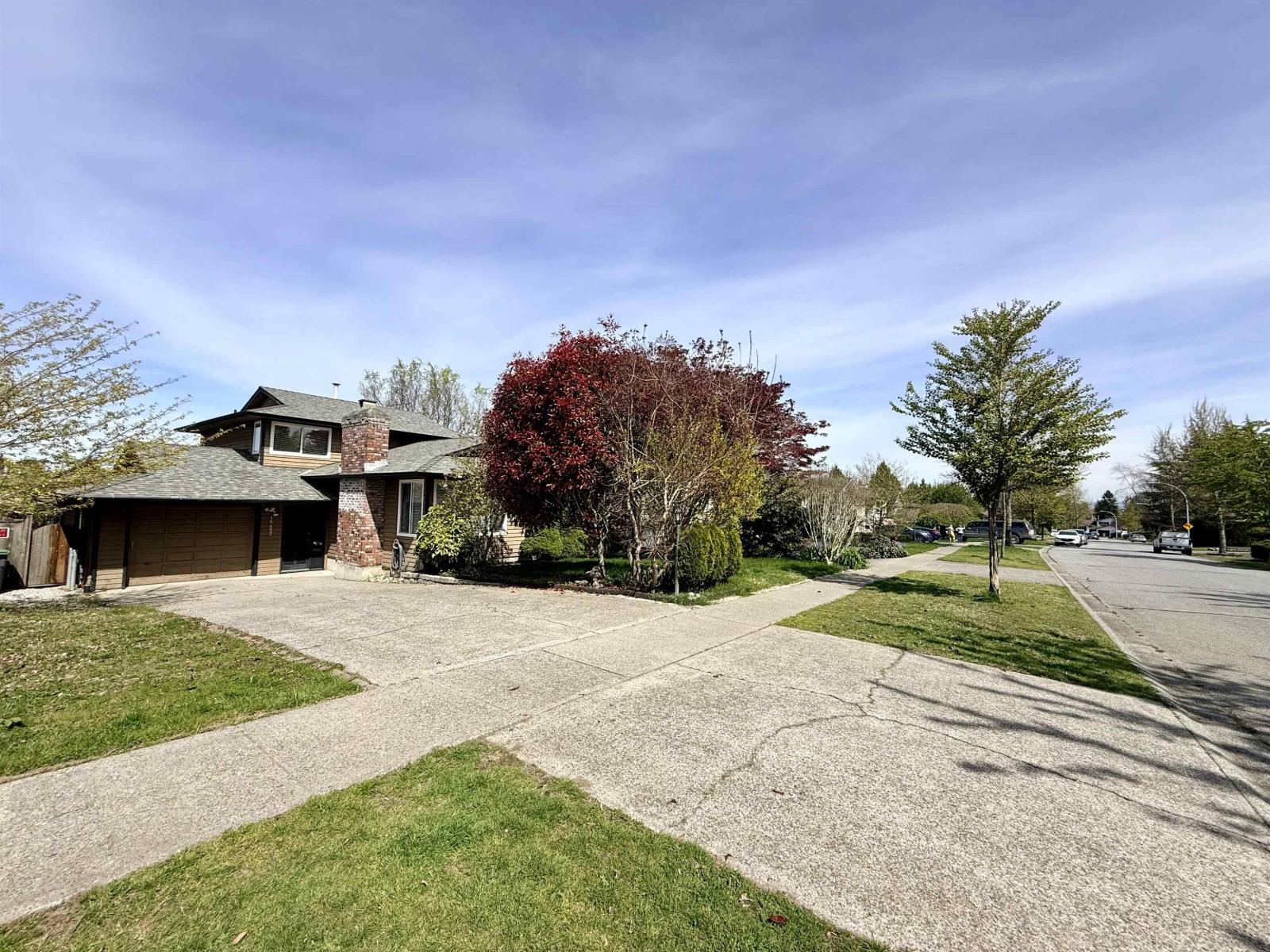 A house with a driveway and trees in front.