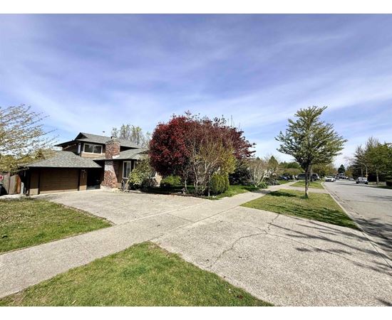 A house with a driveway and trees in front.
