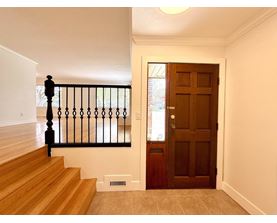 A brown door is at the end of a hallway.