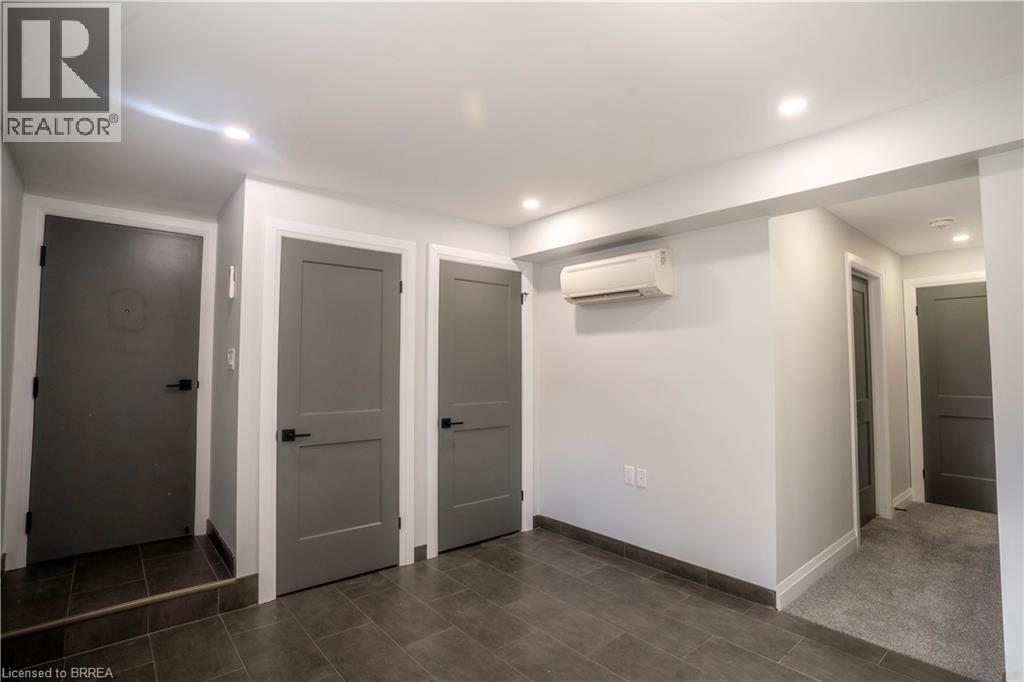 A room with a white wall and a grey floor with a door on the left.