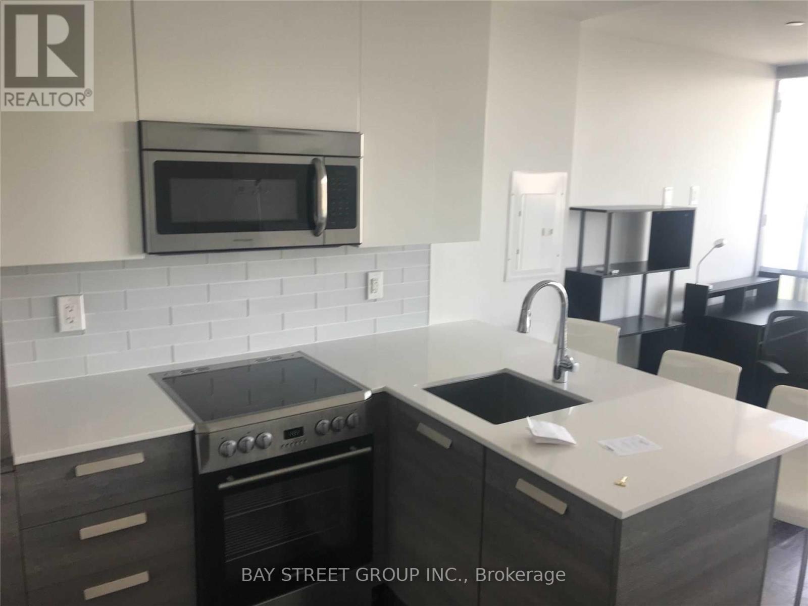 A modern kitchen with a stove top oven and microwave above it.