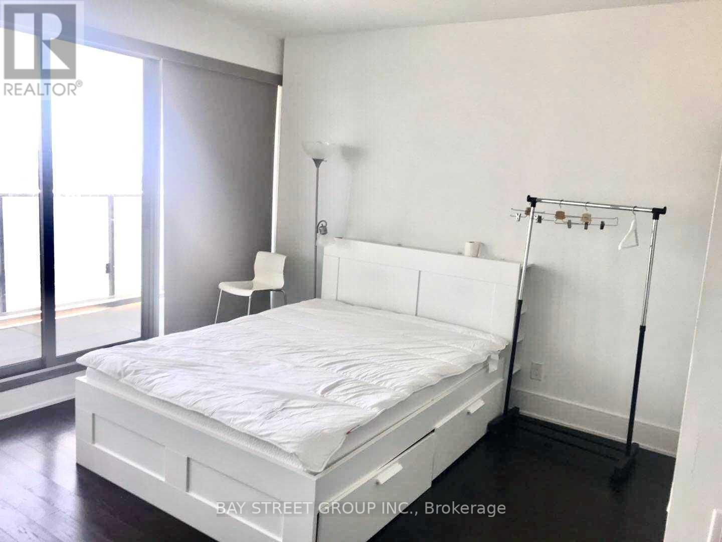 A bedroom with a bed, desk, and chair.