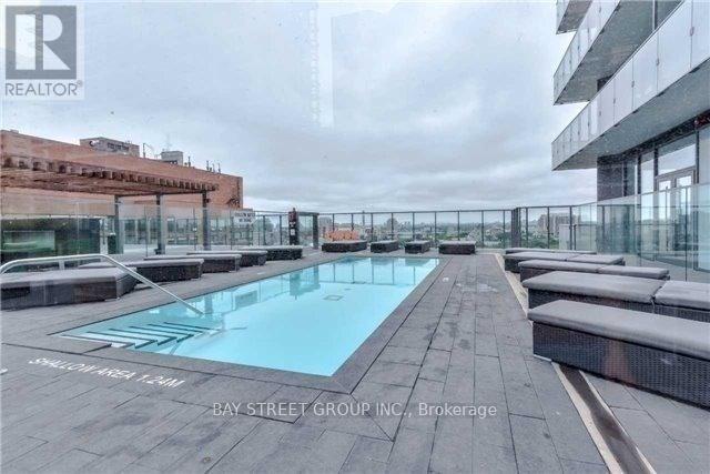 A pool area with a glass railing and a building in the background.