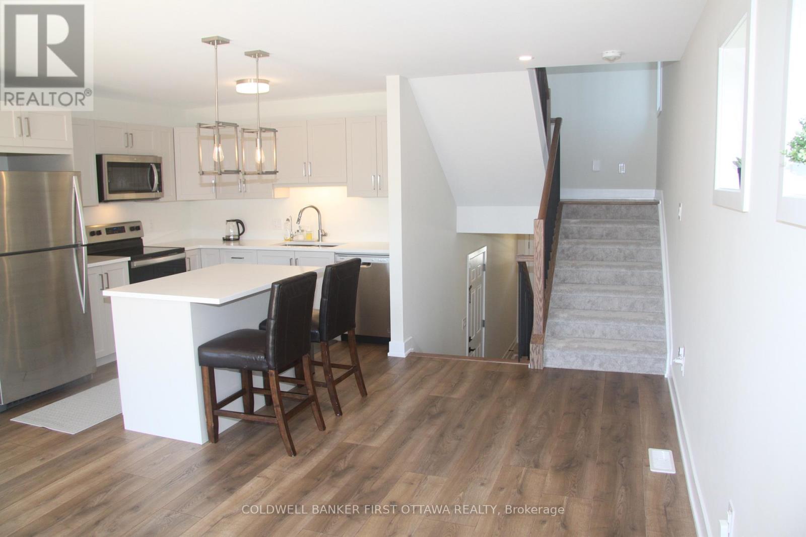 A kitchen with a refrigerator, microwave, and stove top oven.