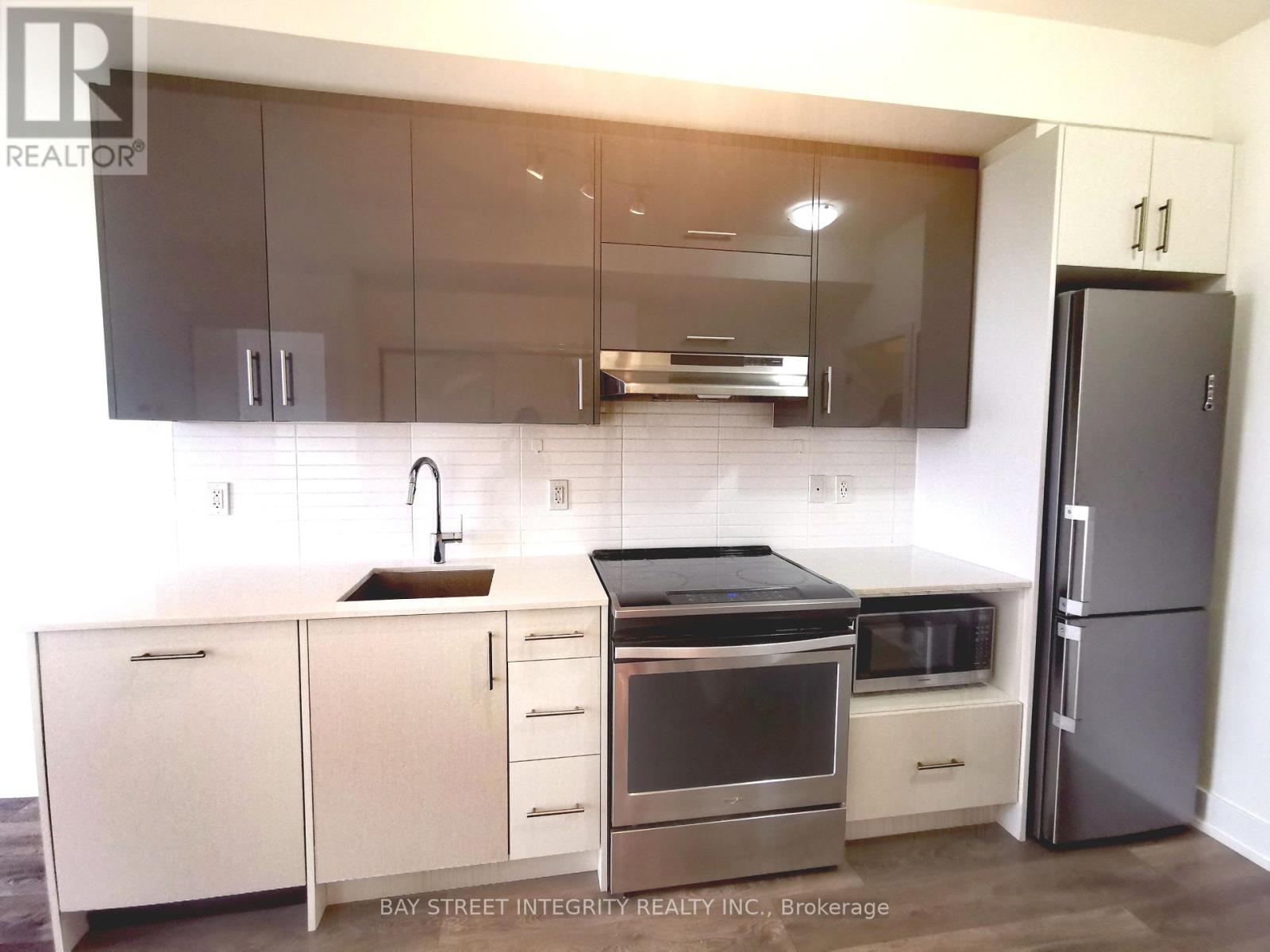 A modern kitchen with a stainless steel refrigerator and white cabinets.