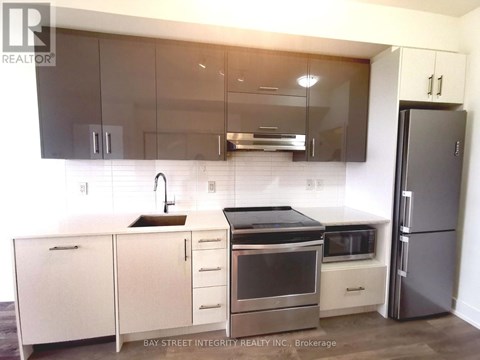 A modern kitchen with a stainless steel refrigerator and white cabinets.