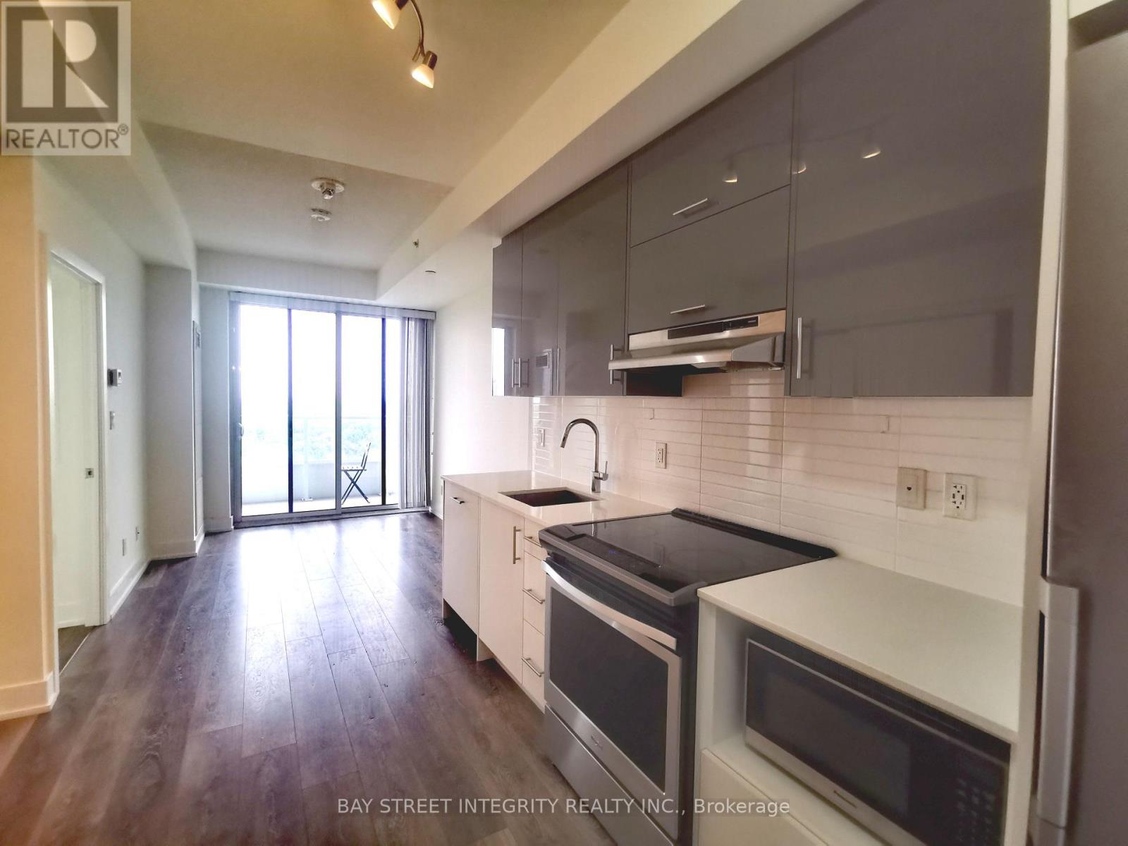 A modern kitchen with dark wood floors and white appliances.