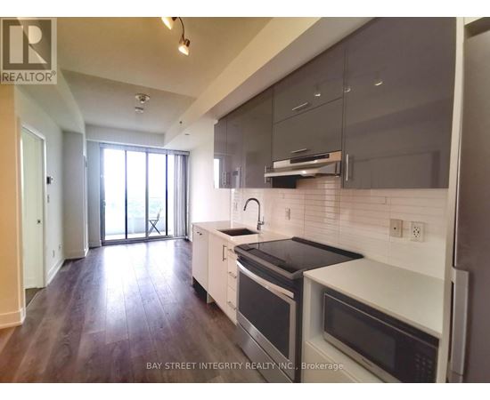 A modern kitchen with dark wood floors and white appliances.