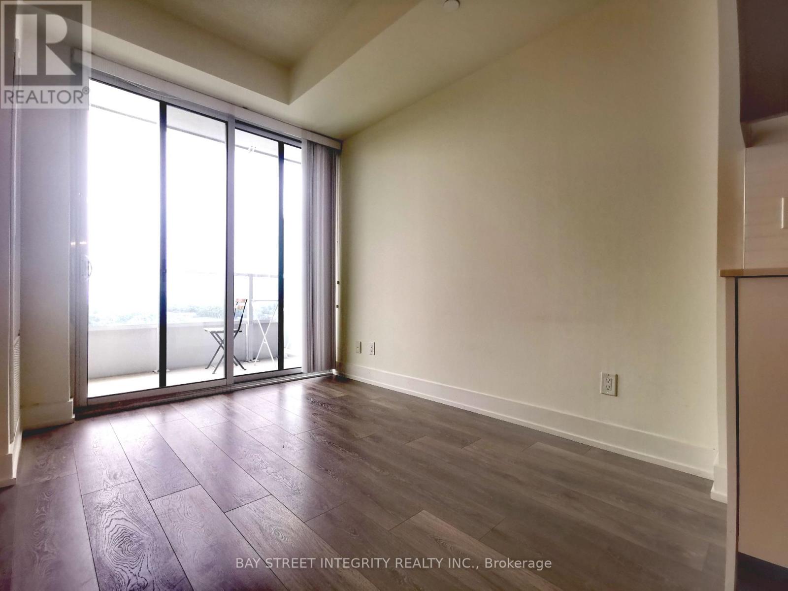 A room with a sliding glass door and wooden flooring.