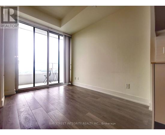 A room with a sliding glass door and wooden flooring.