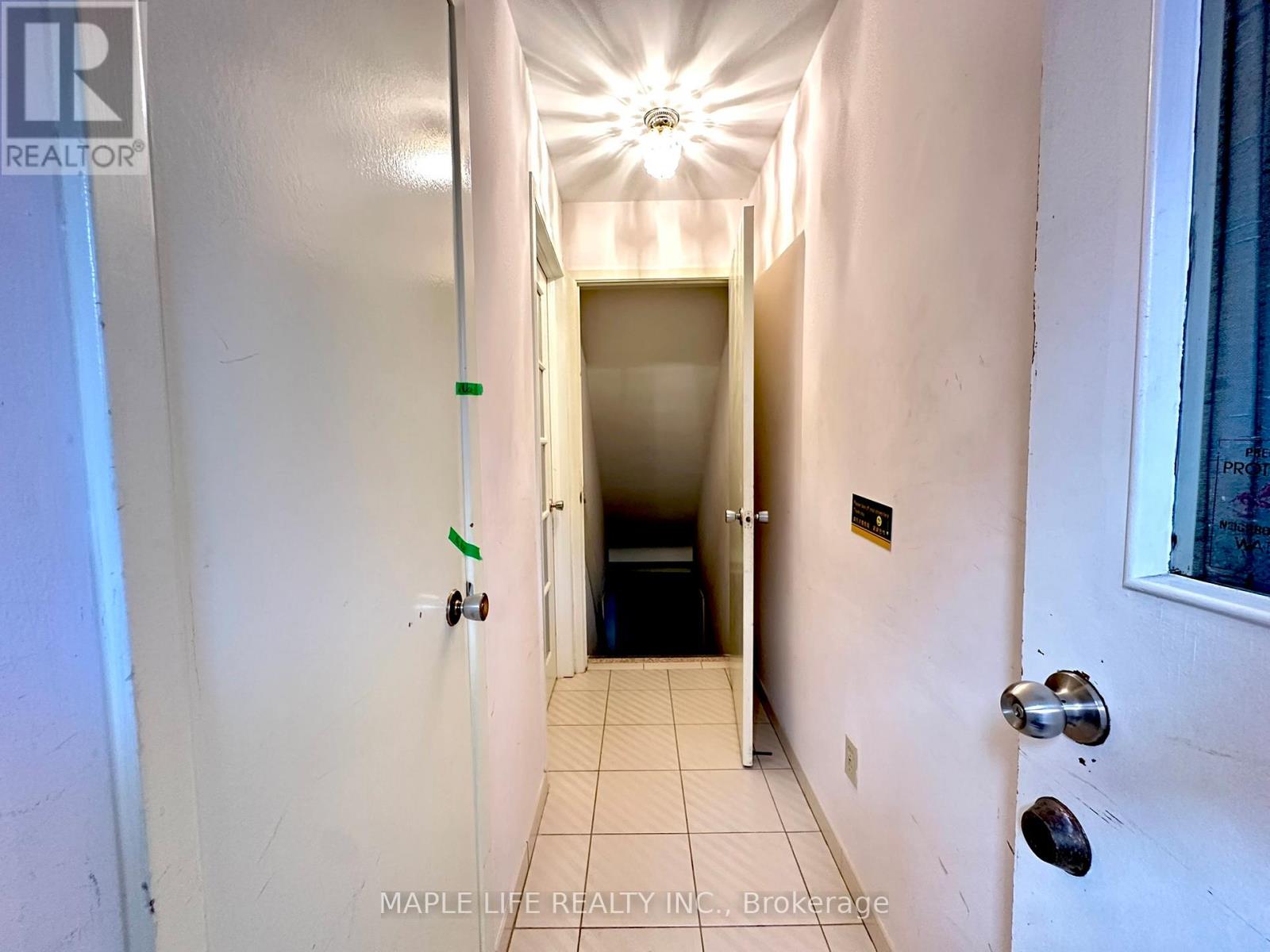 A hallway with a light on the ceiling and a door at the end.
