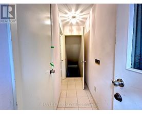 A hallway with a light on the ceiling and a door at the end.