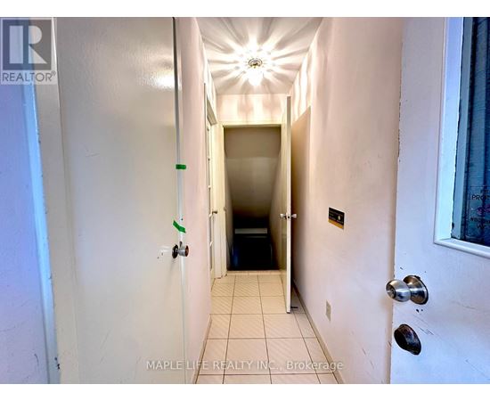 A hallway with a light on the ceiling and a door at the end.