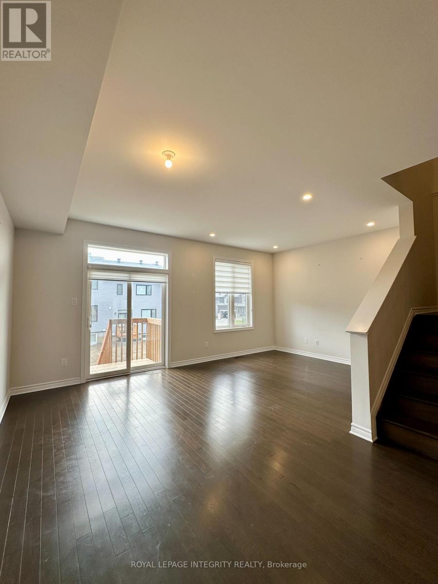 A spacious room with wooden floors and a staircase on the right side.