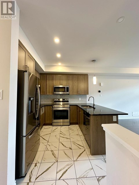 A modern kitchen with a refrigerator, oven, and microwave.