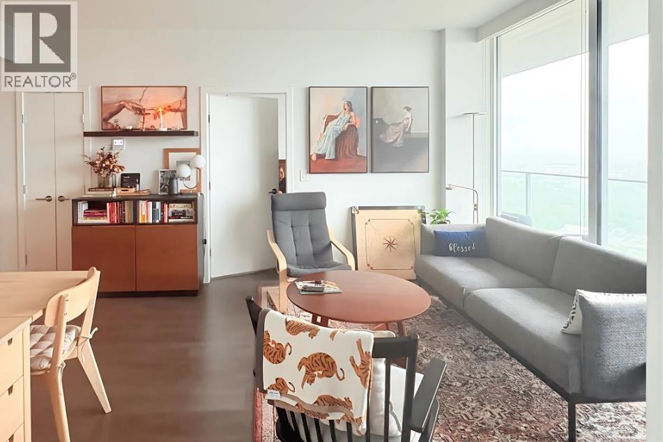 A living room with a grey couch, a wooden table, and a painting on the wall.