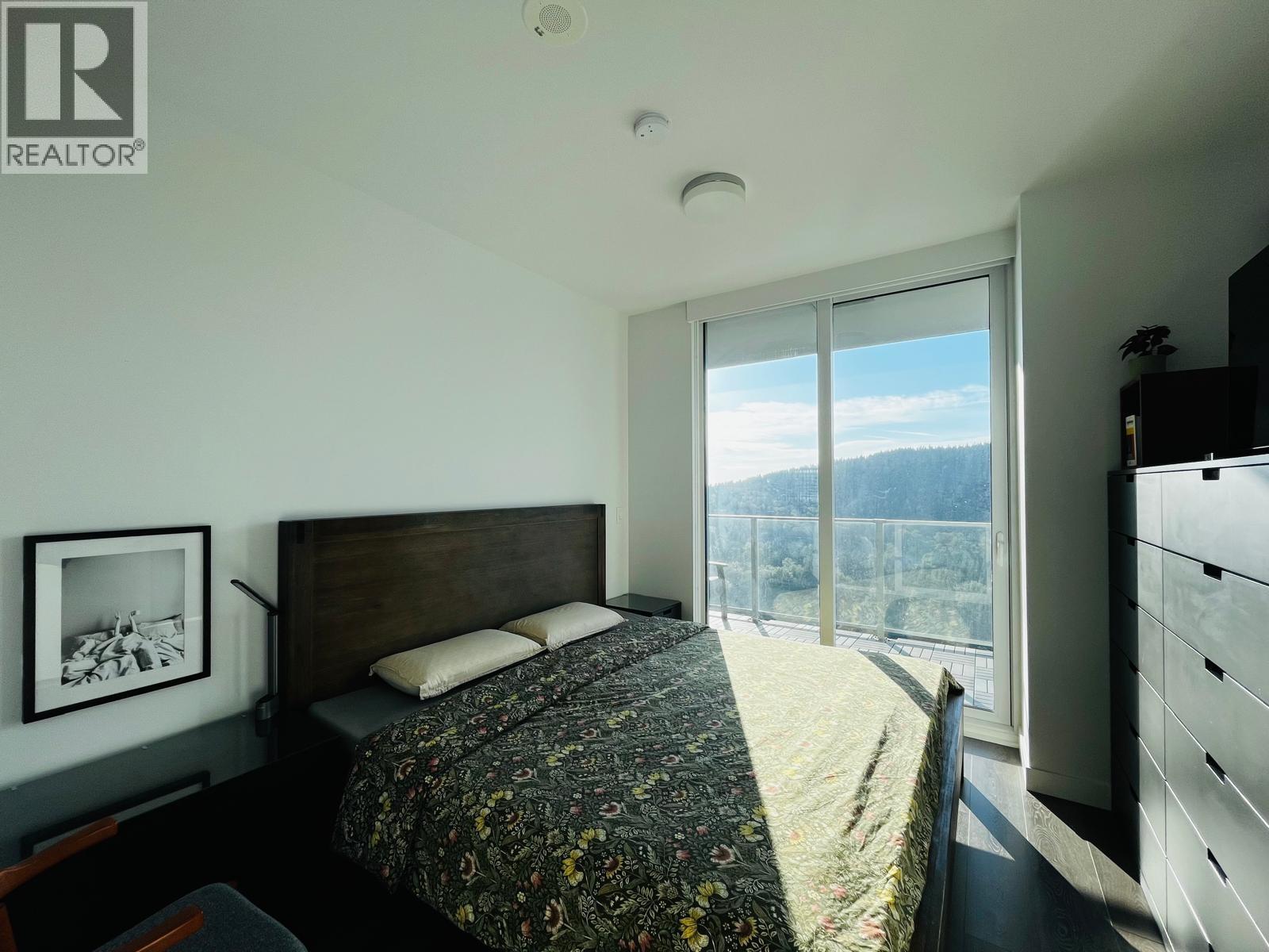 A bedroom with a large bed and a view of the mountains outside the window.