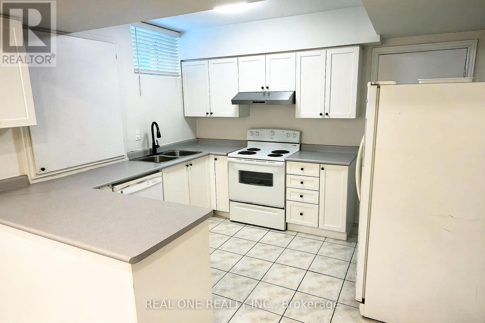 A white kitchen with a refrigerator on the right.