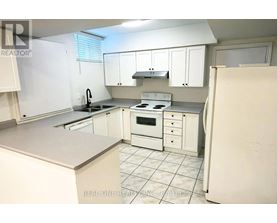 A white kitchen with a refrigerator on the right.