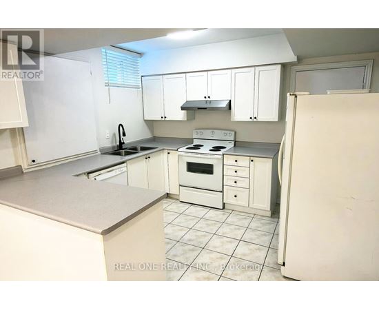 A white kitchen with a refrigerator on the right.
