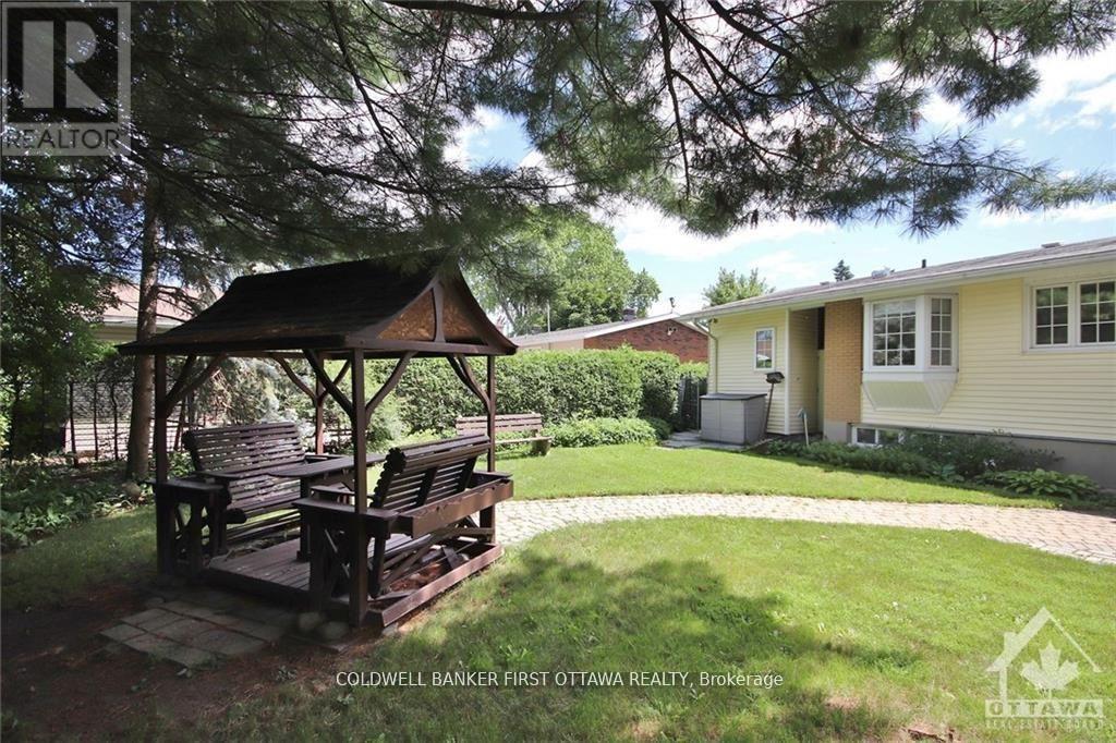 A gazebo sits in a grassy yard in front of a house.