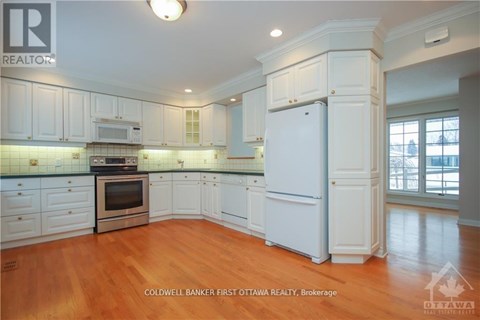 A kitchen with white cabinets and a wooden floor.