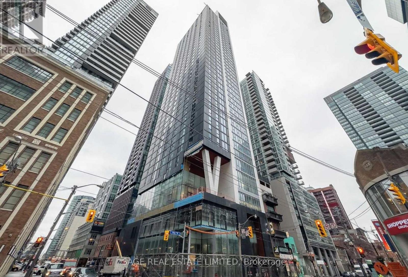 A tall glass building stands in the middle of a city street.