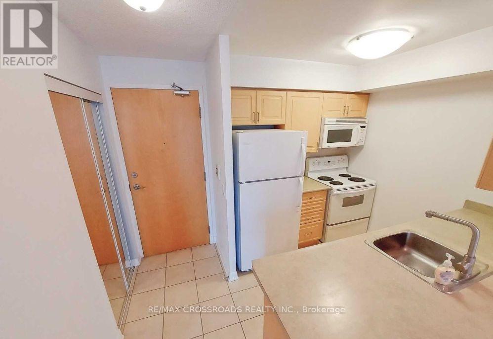 A kitchen with a sink, refrigerator, and microwave.