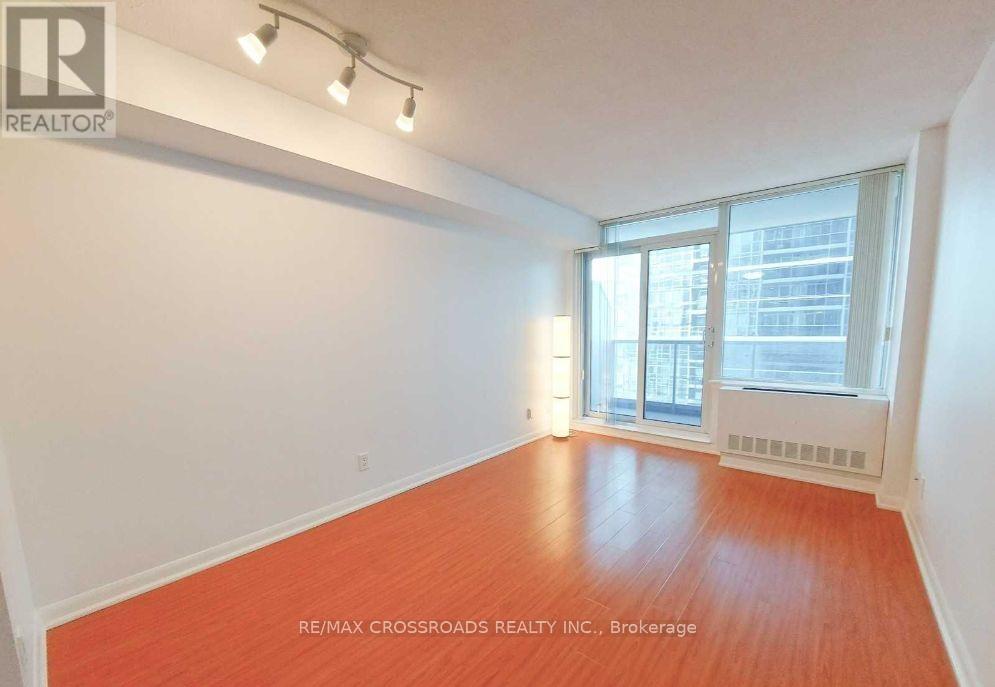 A room with a wooden floor and a window overlooking a cityscape.