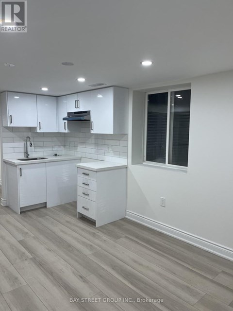 A white kitchen with a sink and a window.
