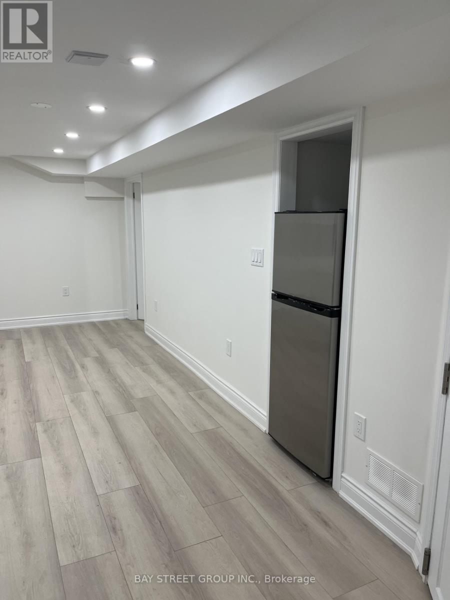 A kitchen area with a refrigerator and wooden flooring.