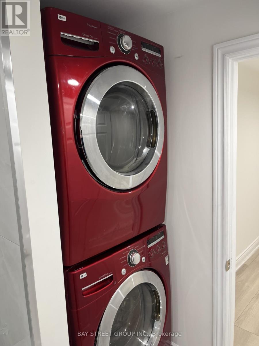 Two red front load washing machines in a laundry room.