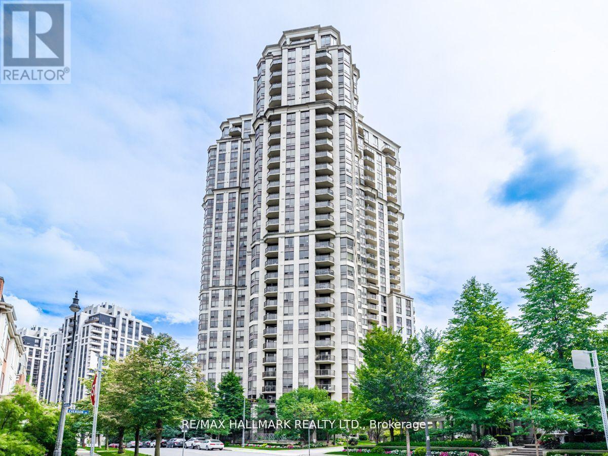 A tall building with many windows is surrounded by trees.