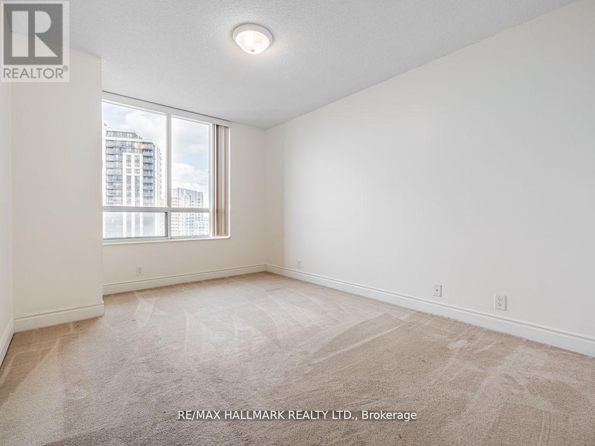 A spacious room with a carpeted floor and a window overlooking a cityscape.