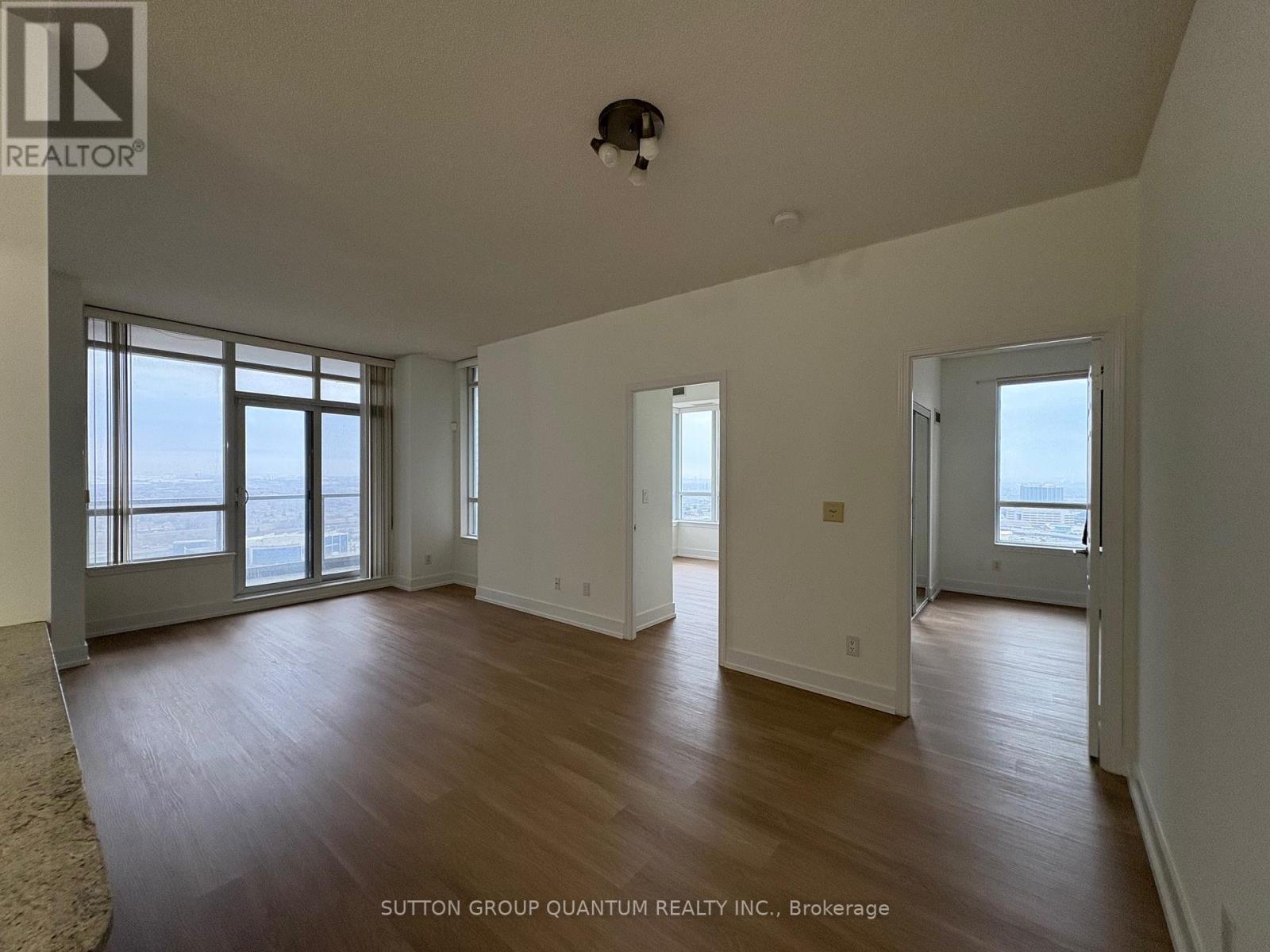 A large, empty room with wood floors and a view of the ocean through the windows.