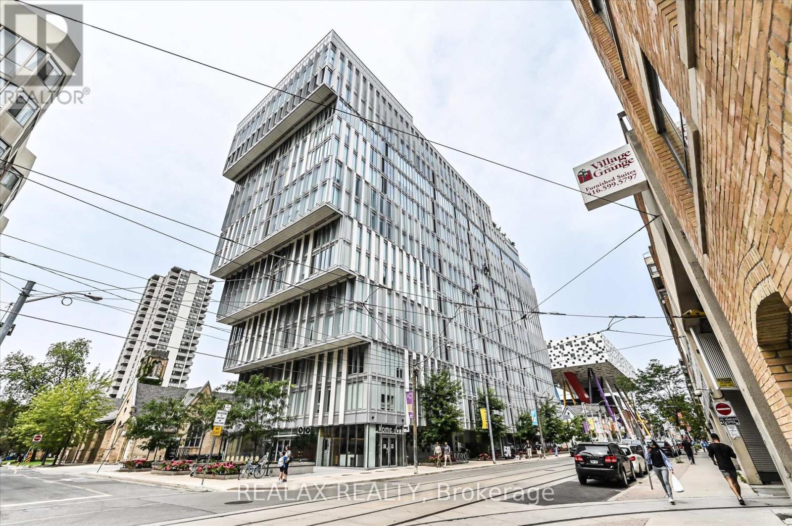 A modern building with a glass facade is located on a busy street.